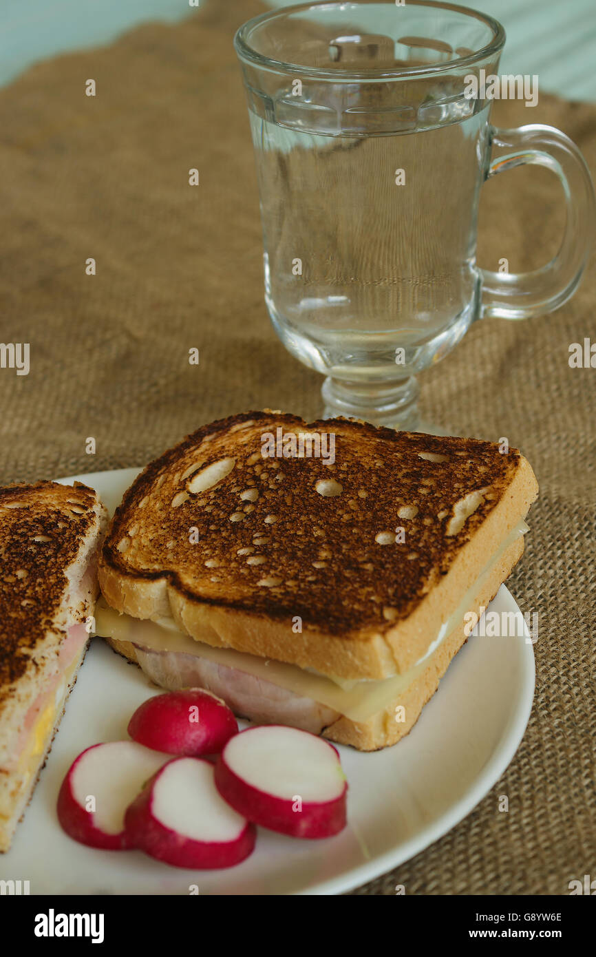 toast with cheese and bacon on a white plate with sliced radishes in a glass of soda Stock Photo