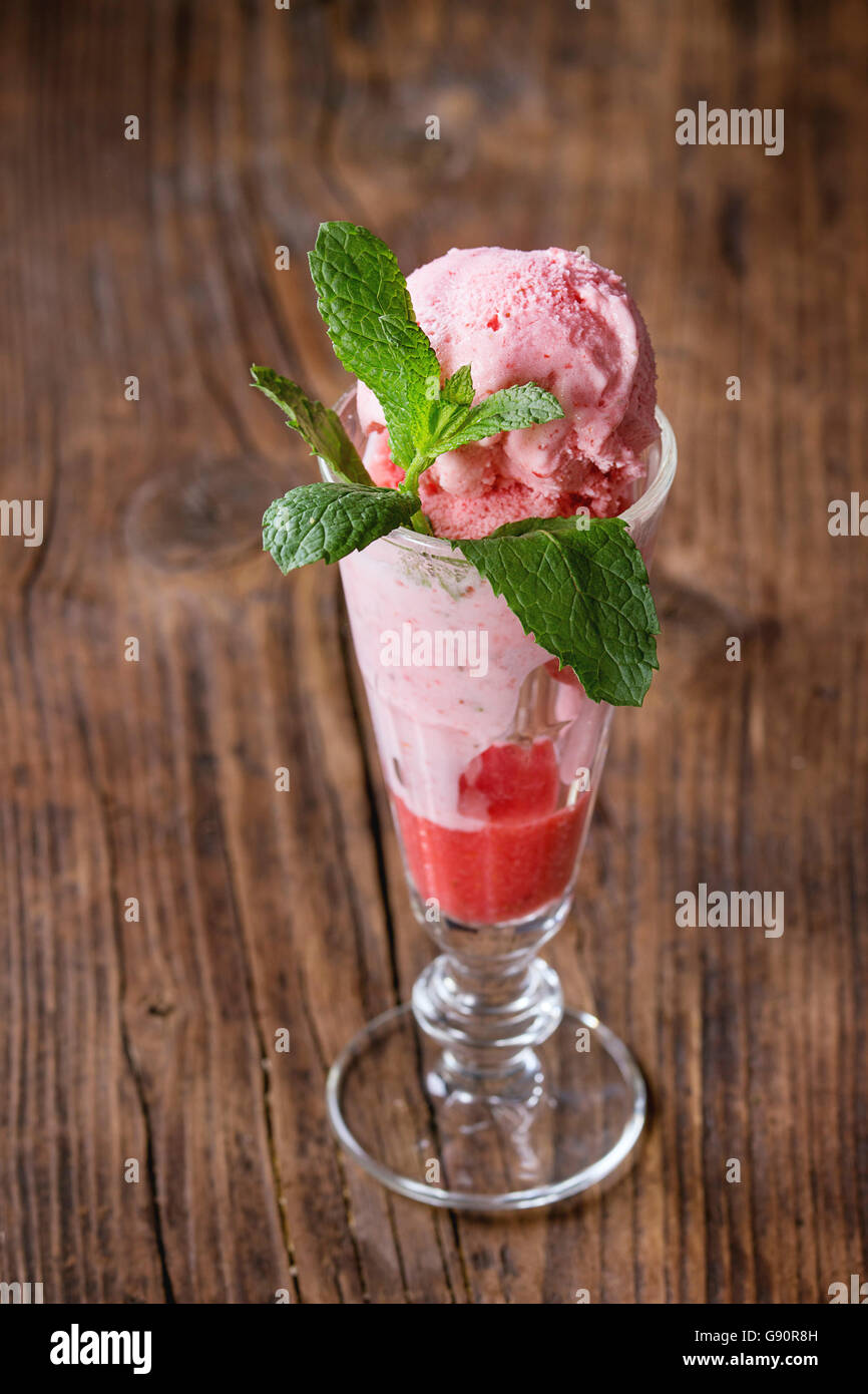 Glass of strawberry dessert with sorbet and mint, served over wooden textured background. Stock Photo