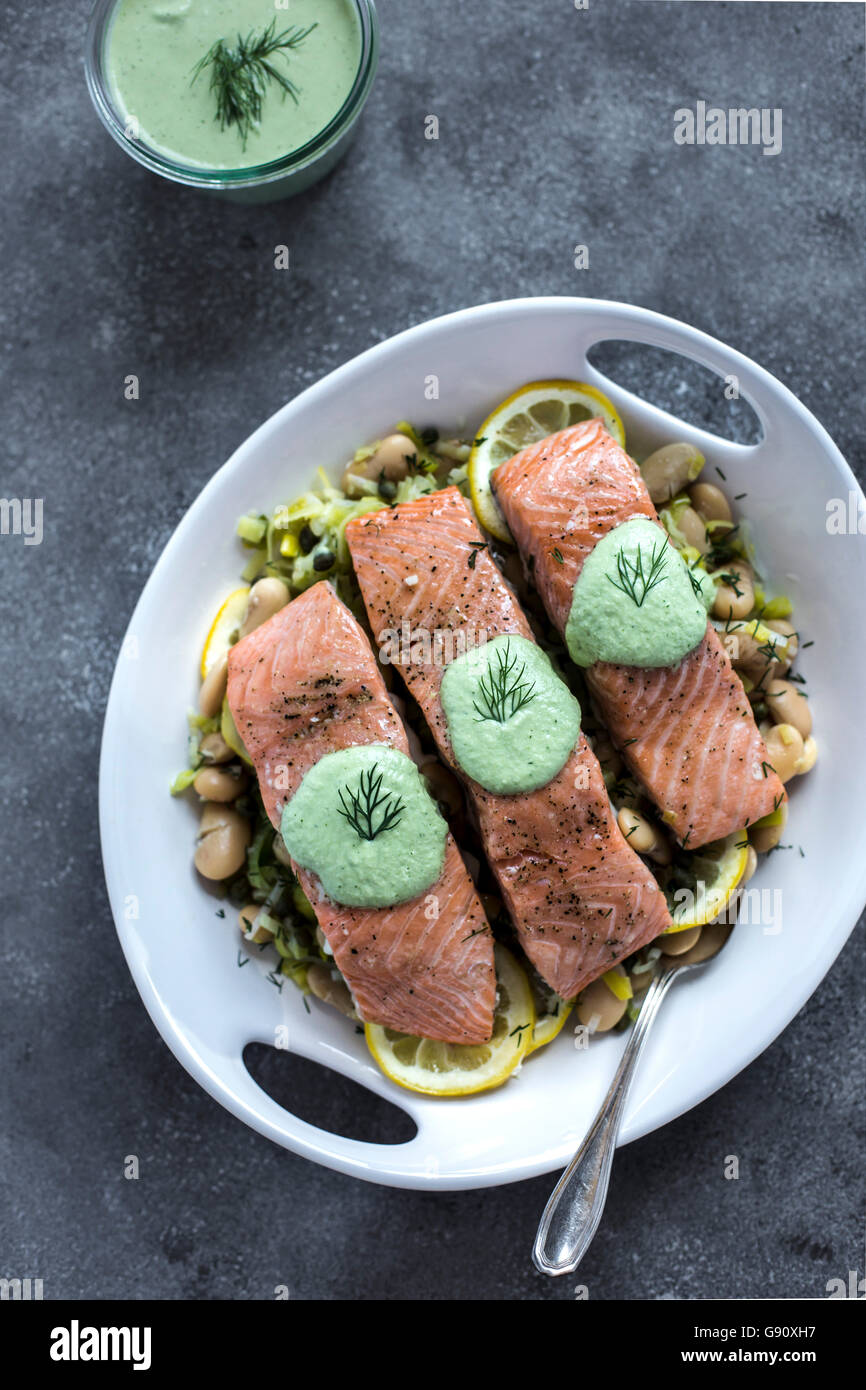 A plate white butter beans topped with oven baked salmon slices is photographed from the front view. photographed from the top ( Stock Photo