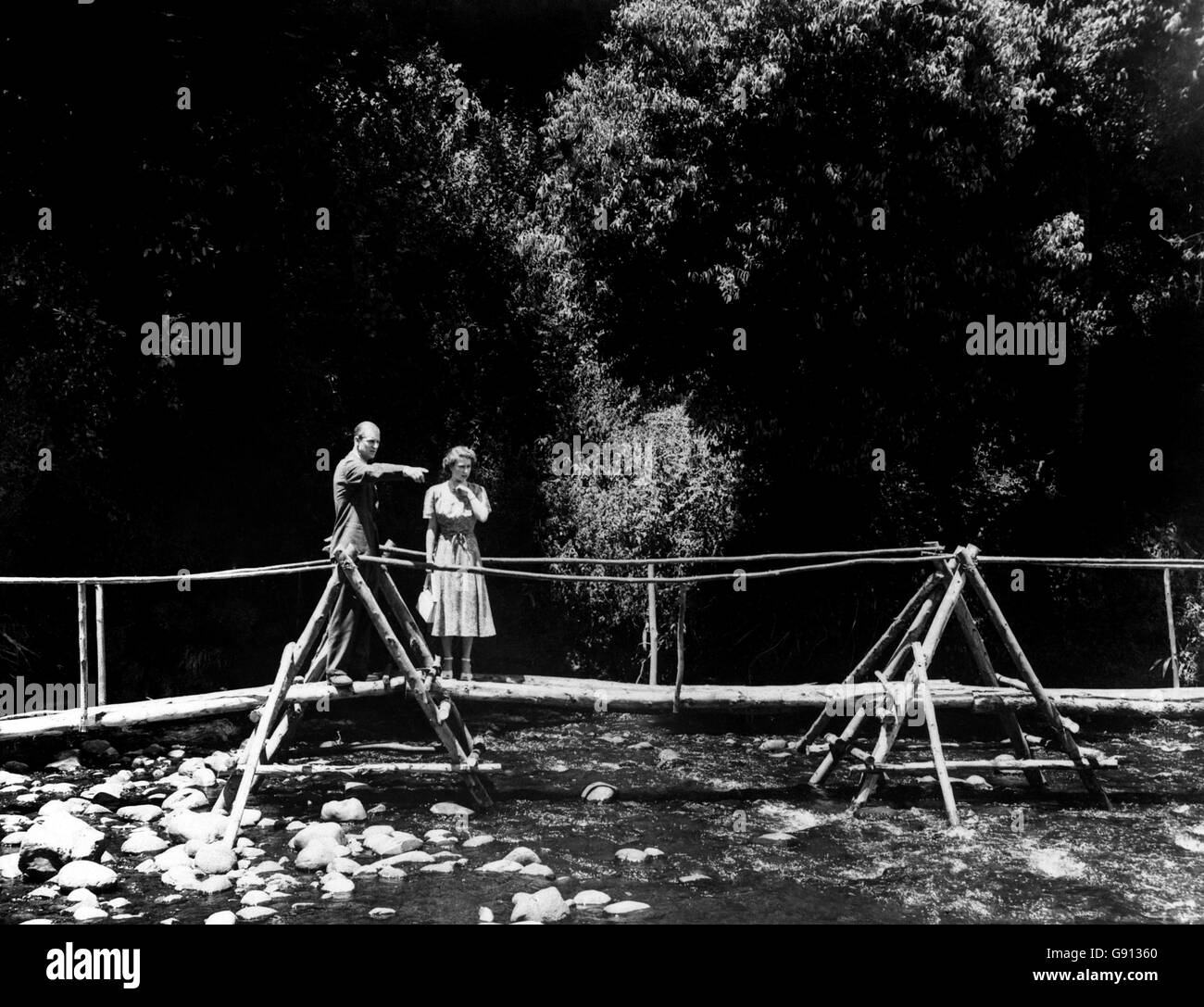 Princess Elizabeth and the Duke of Edinburgh pause on the rustic bridge in the grounds of the Royal Lodge, Sagana, their wedding present from the people of Kenya. Stock Photo