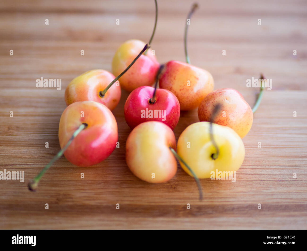 Beautiful, sweet, and delicious Rainier cherries on a bamboo cutting board. Stock Photo