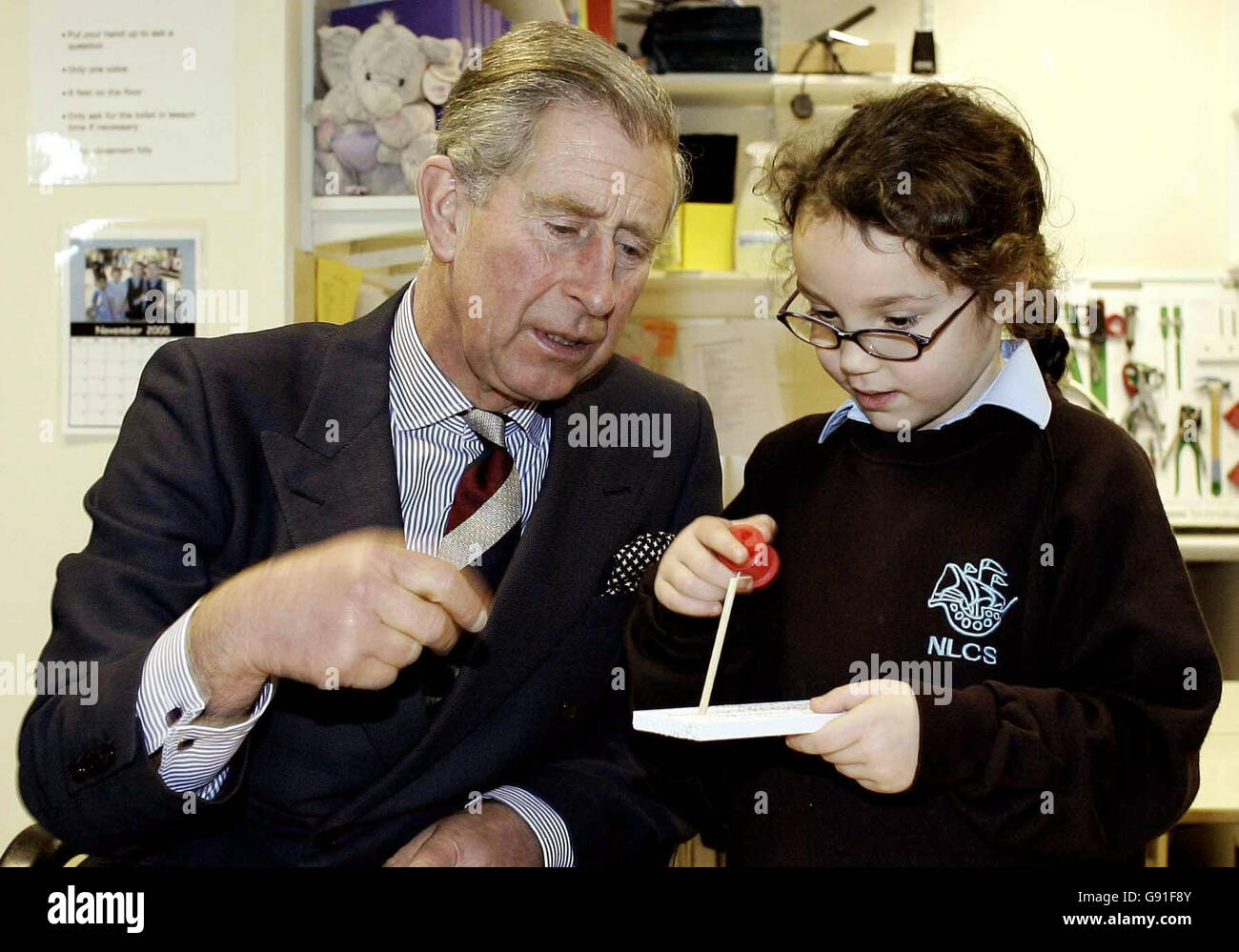 Prince of Wales helps Georgie Strauss, 7, with her woodwork during a visit to the North London Collegiate School, Monday 21 November 2005 after he had earlier met volunteers who are helping rebuild parts of Sri Lanka hit by the Boxing Day tsunami by harnessing methane gas from buffalo.Charles visited the Department for Education and Skills in central London, where he met three women who helped set up an 'eco-centre' in one of the worst hit regions. But they did not manage to tell the Prince about one of their more innovative projects - collecting 'bio-gas' from buffalo faeces to fuel nearby Stock Photo