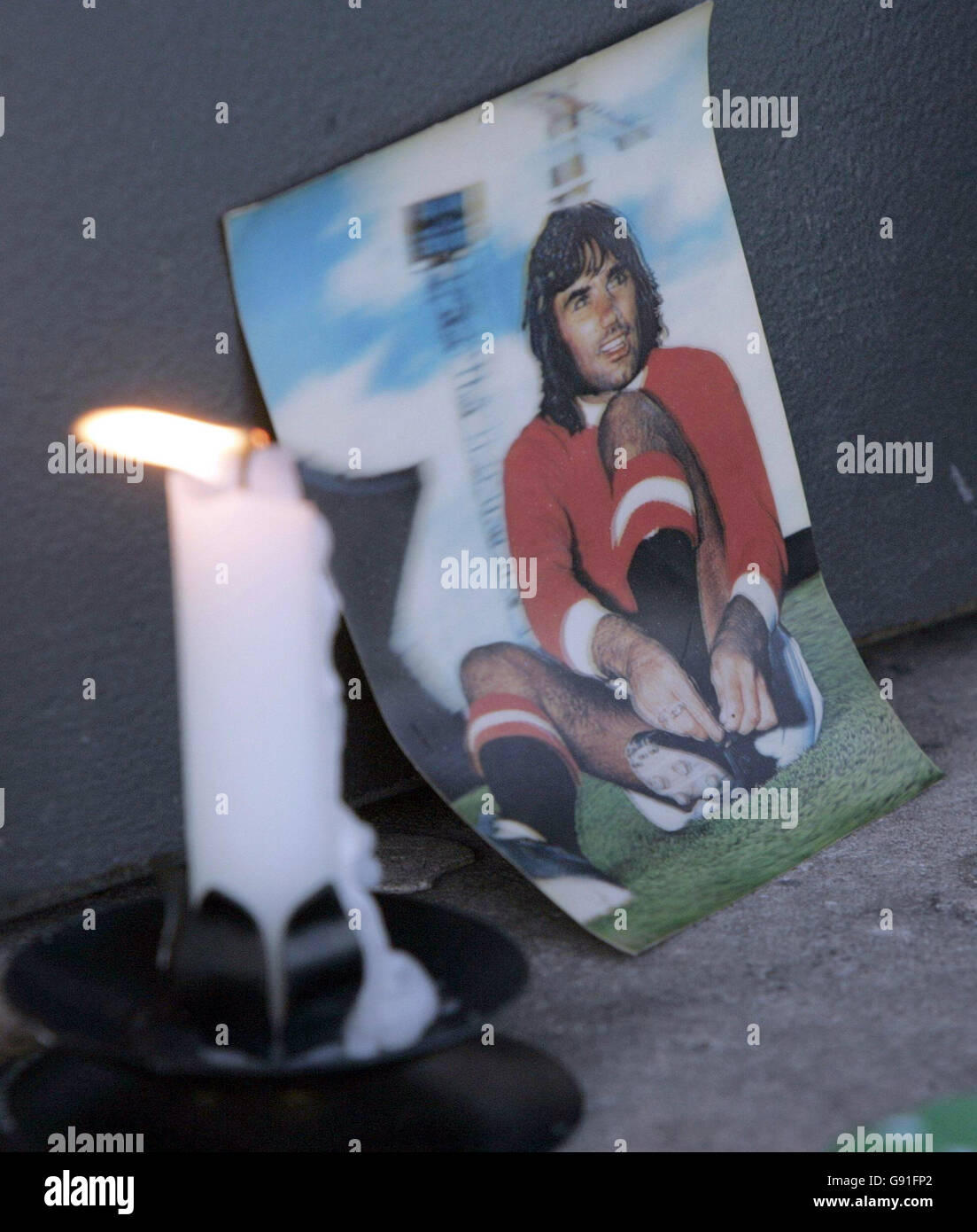 A candle flickers next to a photograph of George Best outside ...