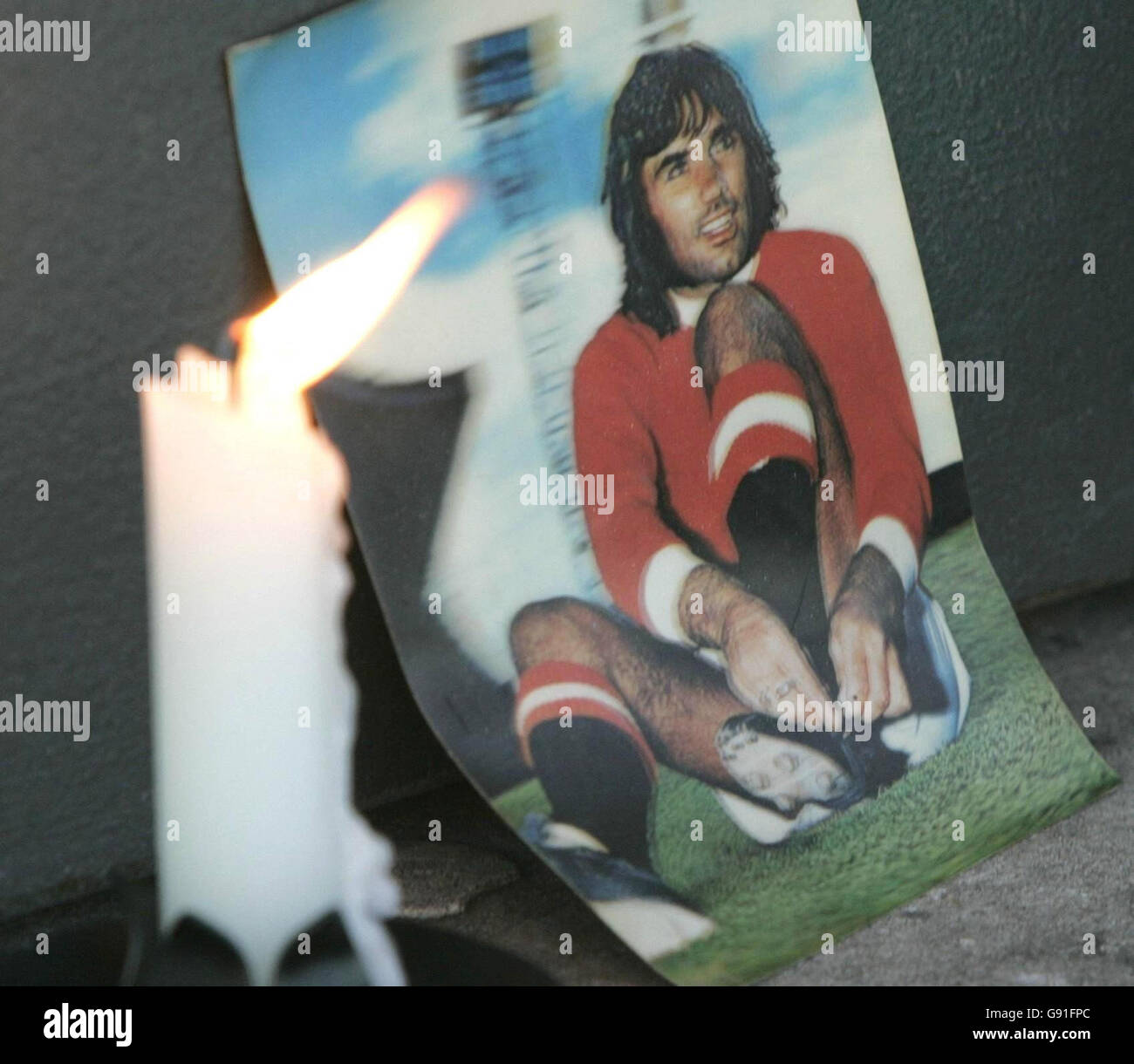 A candle flickers next to a photograph of George Best outside ...