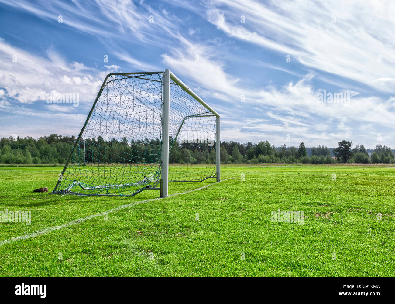 Soccer Goal on Soccer Pitch with a partly cloudy sky and trees. Stock Photo