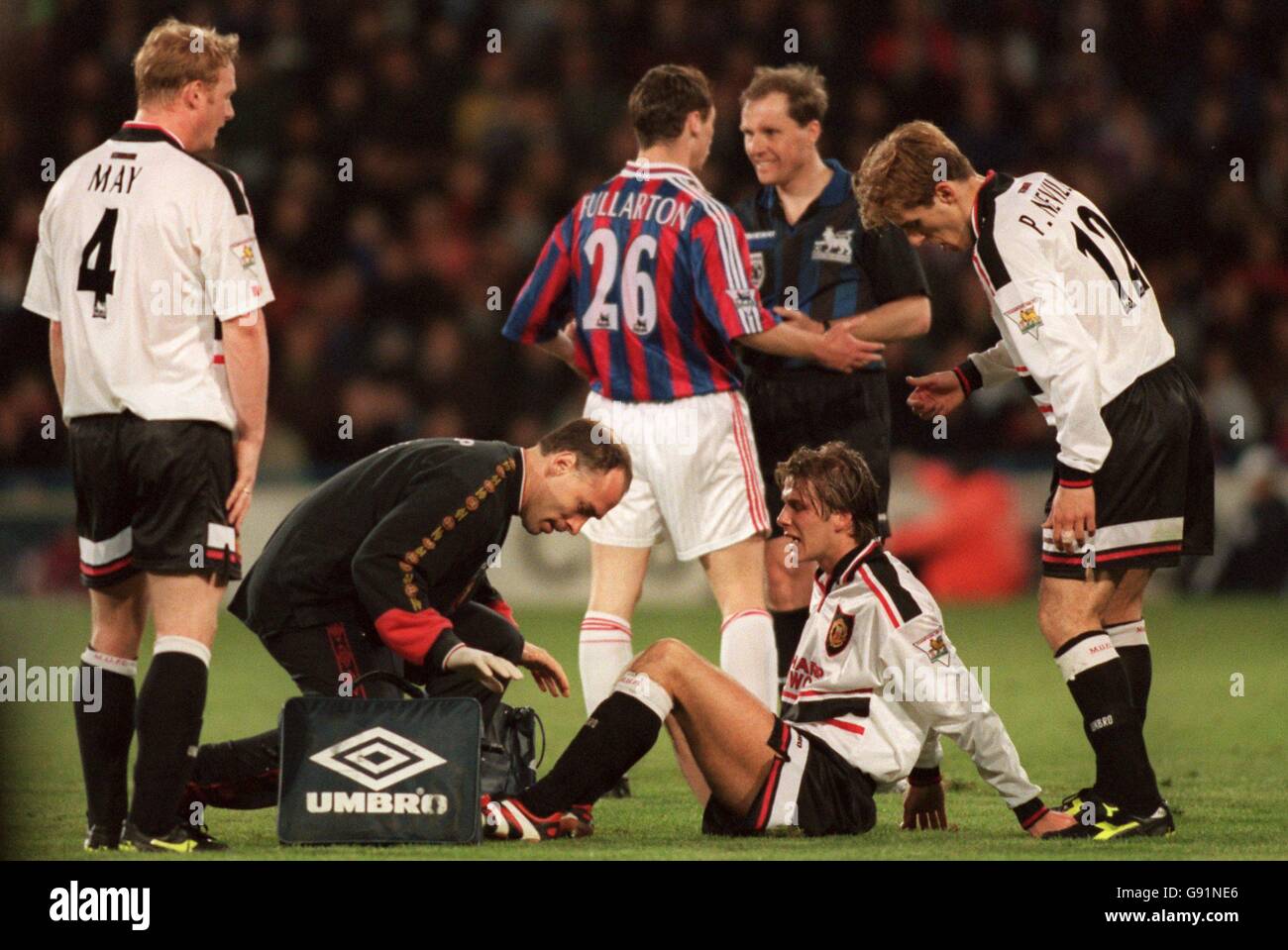 David Beckham of Manchester United (on floor) is treated by his team's physio as Crystal Palace's Jamie Fullarton (back, left) is booked by referee Peter Jones (back, right) Stock Photo
