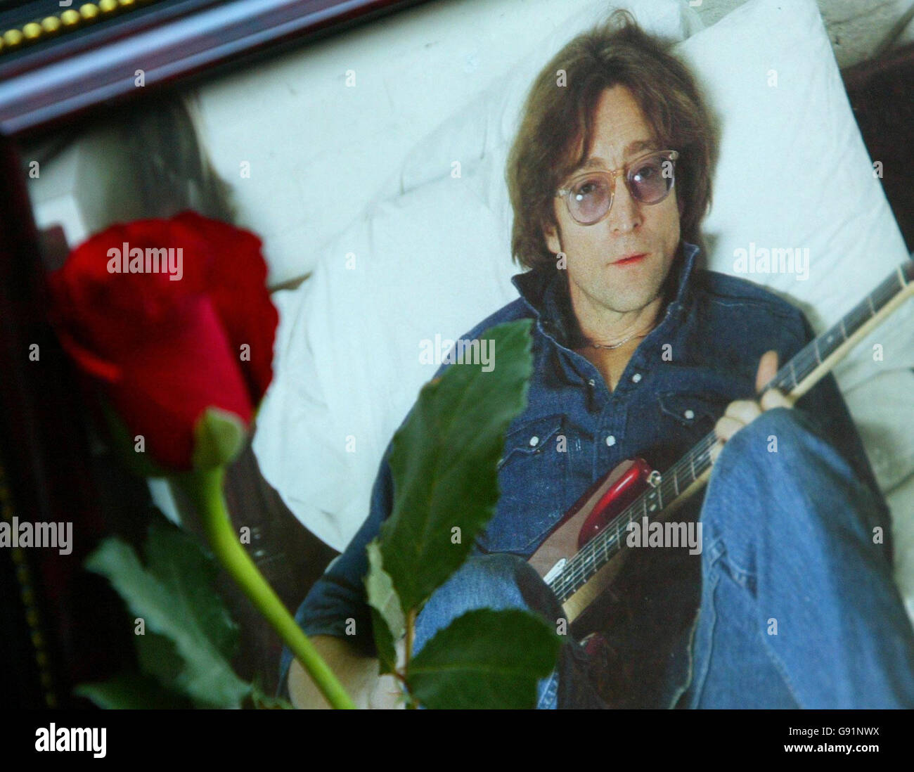 A single red rose is placed next to a photograph of late Beatle John Lennon near to a statue of The Beatles in the Cavern Walk shopping centre in Liverpool on the 25th anniversary of his death, Thursday December 8 2005. Tributes to murdered music icon Lennon will be attached to balloons and released today. More than 1,000 messages to the ex-Beatle, each written on card and attached to a white balloon, will be released from Albert Dock at midday. See PA Story SHOWBIZ Lennon. PRESS ASSOCIATION PHOTO. Photo credit should read: Phil Noble/PA Stock Photo