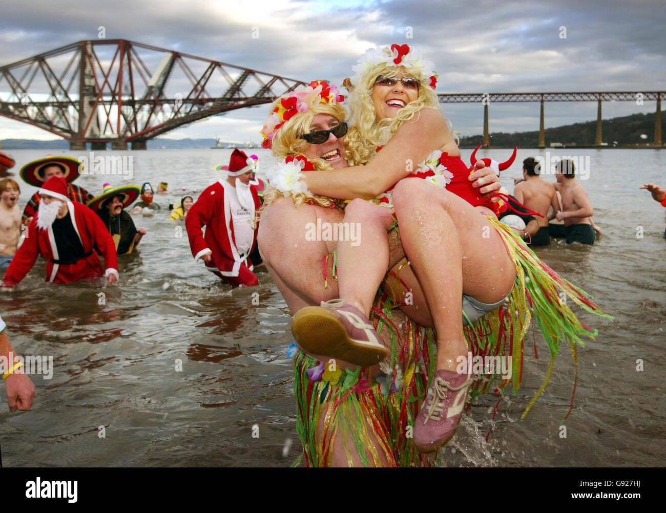 Locals throw themselves into the icy waters of the Firth of Forth for the Loony Dook swim part of the Hogmanay celebrations near the forth rail bridge Edinburgh. Stock Photo