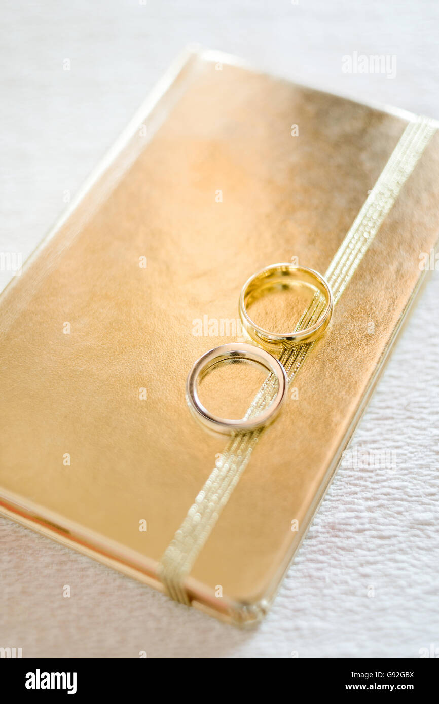 Wedding rings on golden book of memory, selective focus Stock Photo