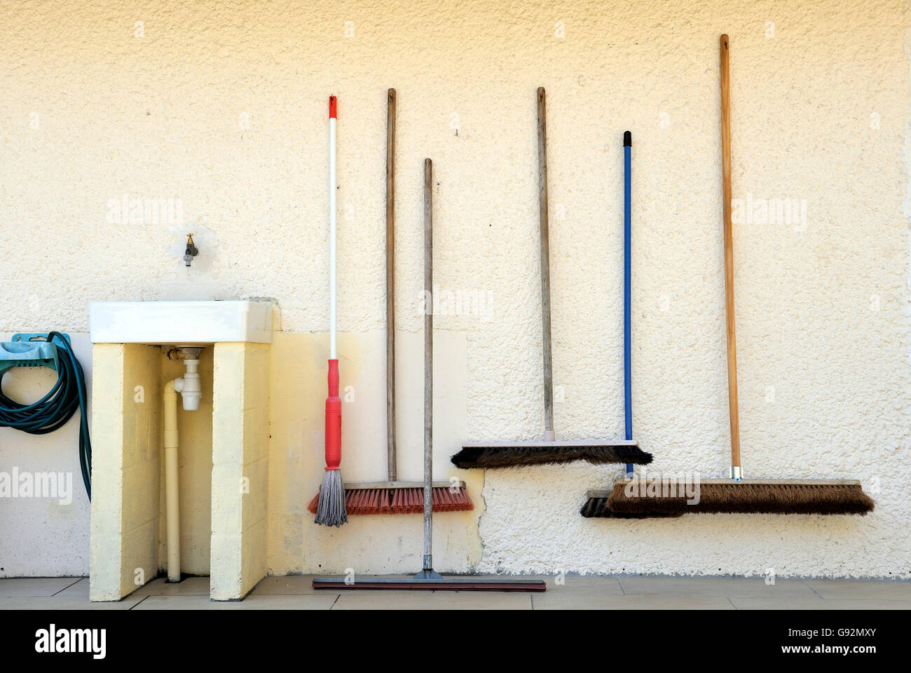 Brooms at a campsite situated next to a sink Stock Photo