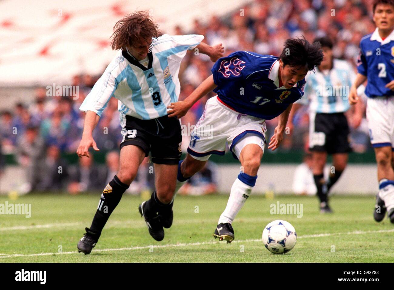 Gabriel Batistuta of Argentina (left) battles for possession of the ball with Yutaka Akita of Japan (right) Stock Photo