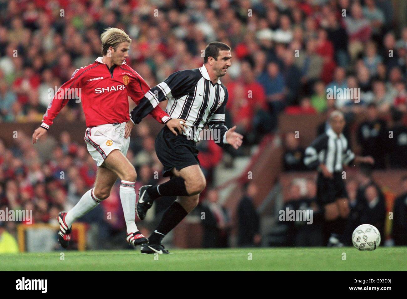 Manchester United's David Beckham (left) battles for the ball with Cantona XI's Eric Cantona (right) Stock Photo