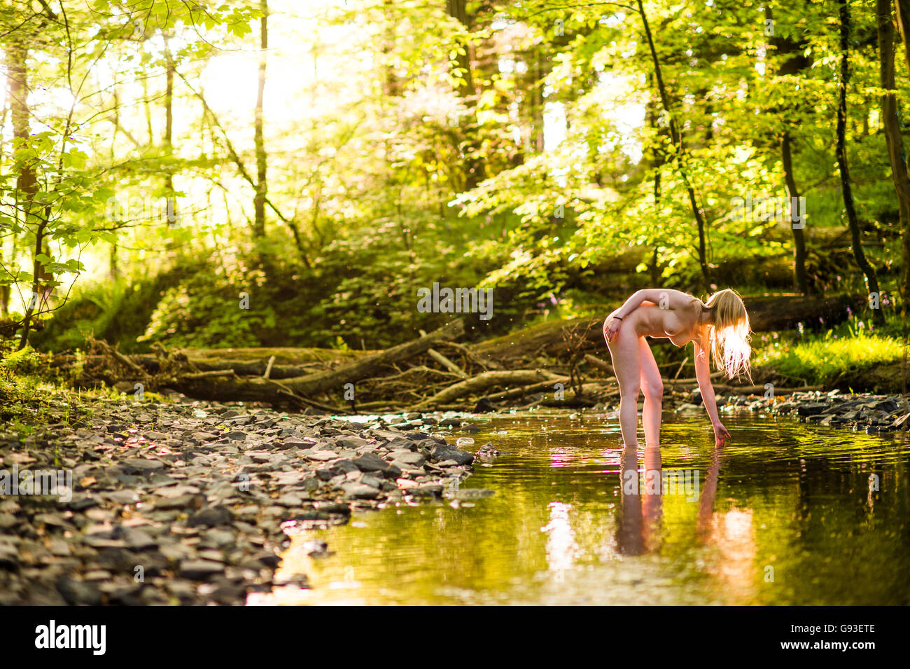 nudist girls in forest Nude in the forest: a backlit young naked blonde woman girl standing in a  stream , bent