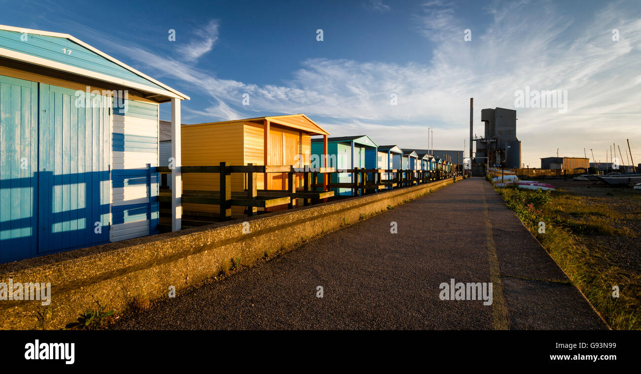 Colourful beach huts leading to the iconic cement works at Whitstable harbour. Stock Photo