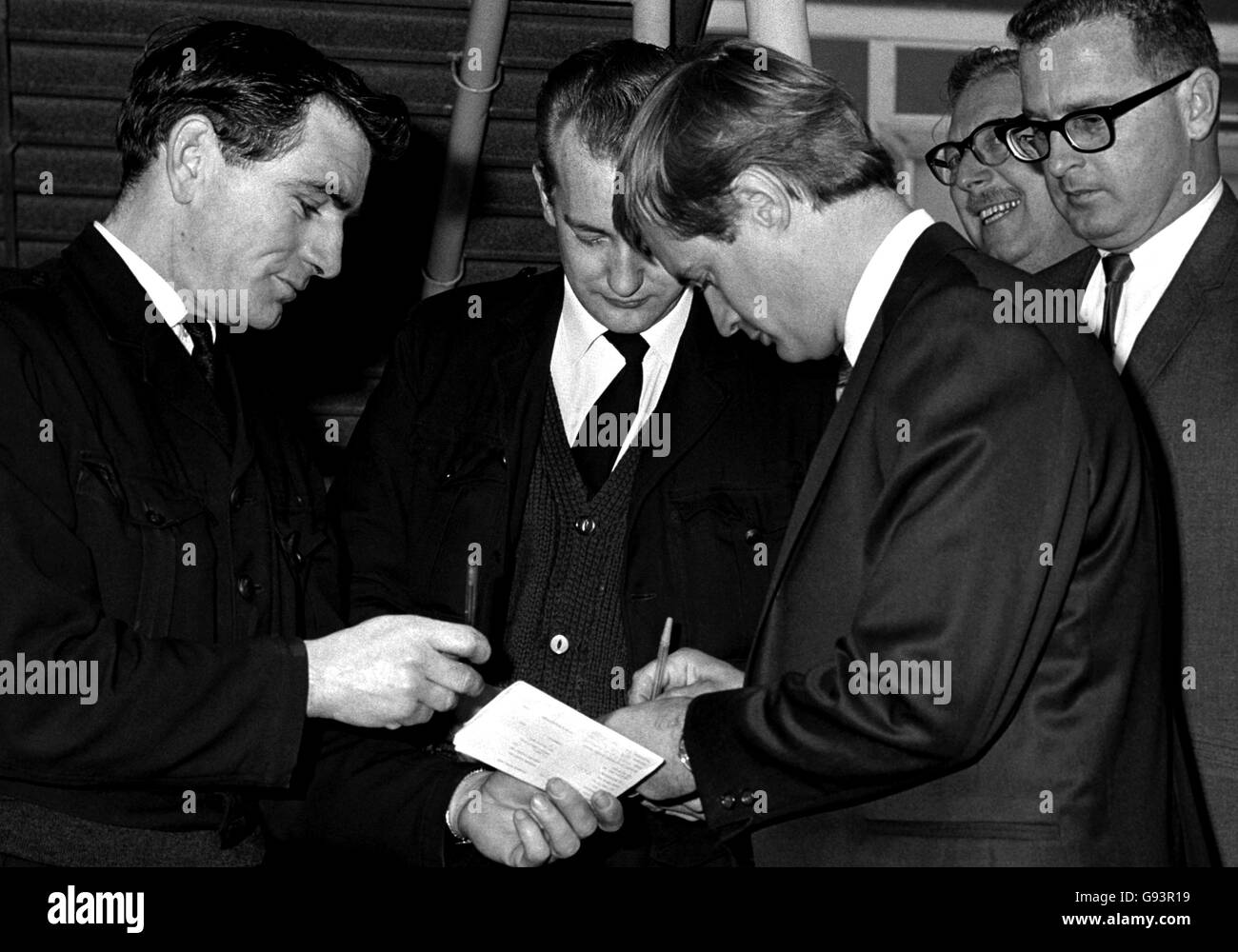 David McCallum who plays Illya Kuryakin in the BBC television series, 'The Man From U.N.C.L.E', signs autographs before leaving for Rome. (fans pictured in background). Stock Photo