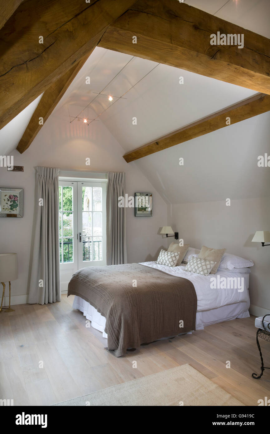 UK. A contemporary bedroom with a high ceiling and original period beam features. Stock Photo