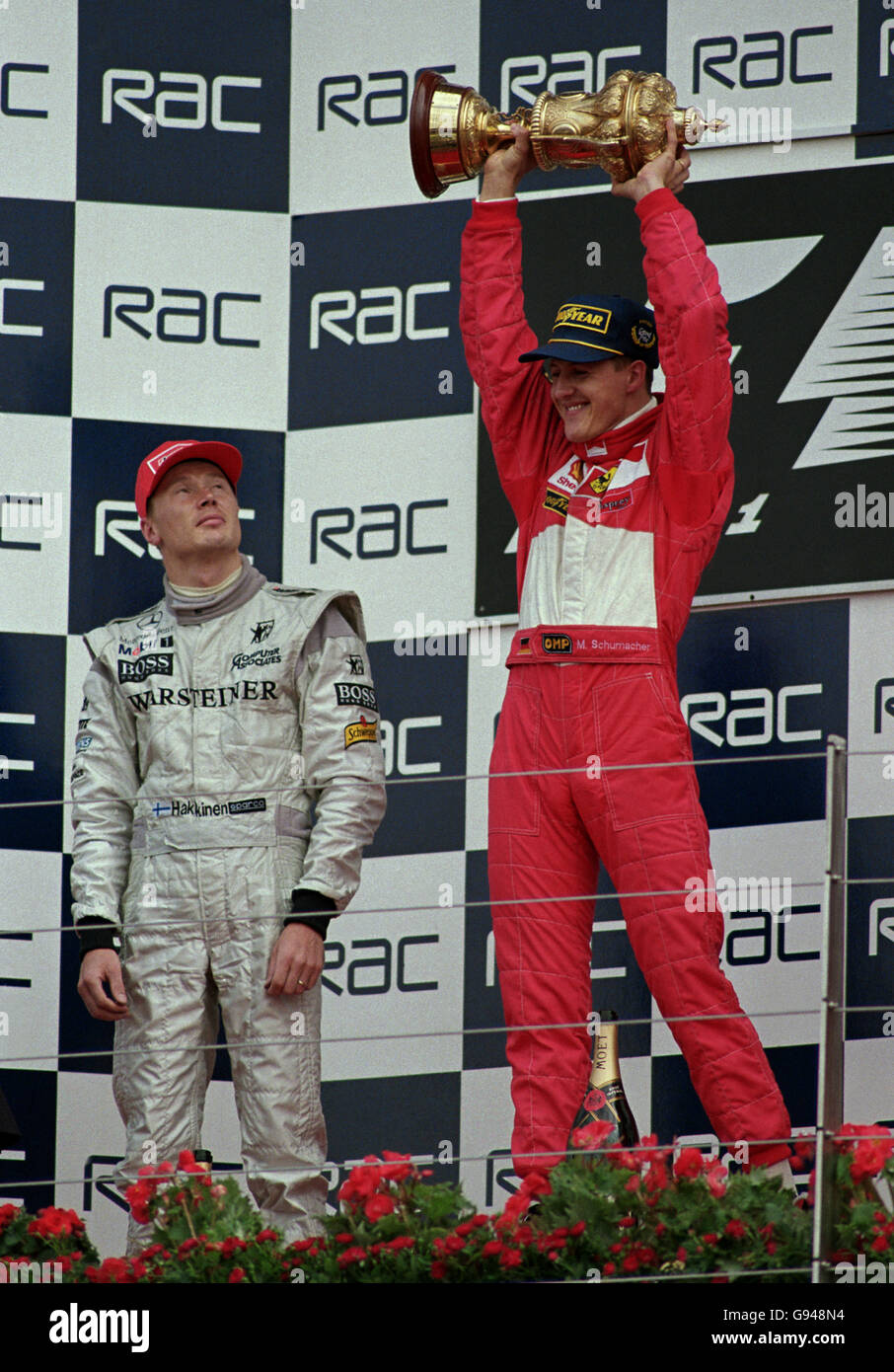 Mika Hakkinen (left) looks on as Michael Schumacher (right) lifts the