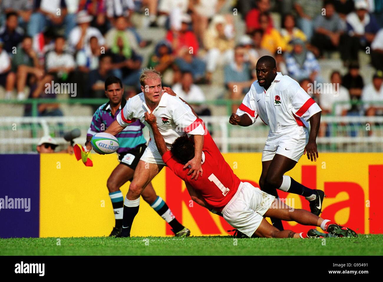 England's Russel Earnshaw (left) passes the ball as he is tackled by Tonga's Tevita Fisilau (centre), watched by England's Nick Baxter (right) Stock Photo