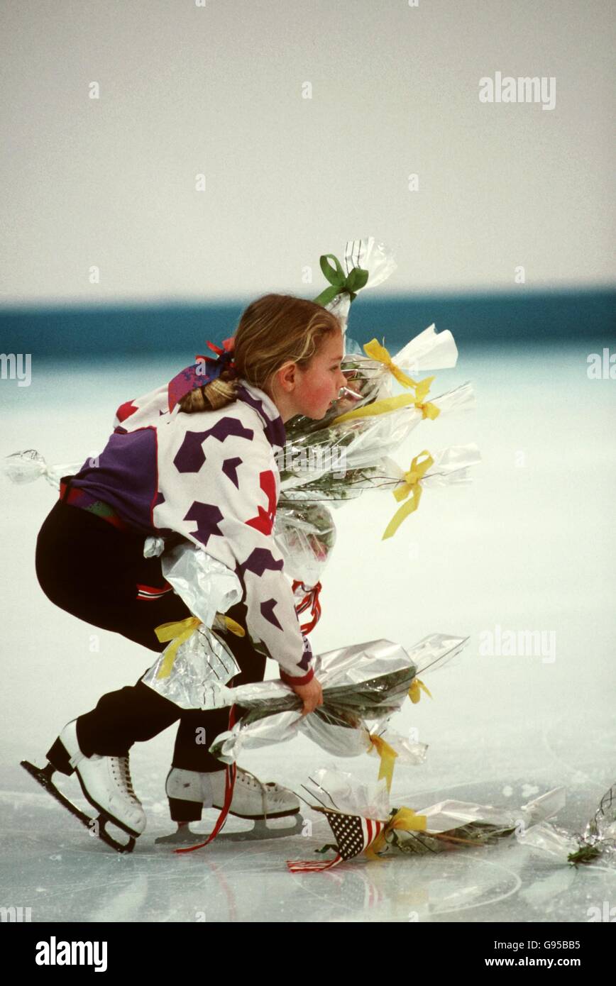 A young girl picks up the bouquets of flowers thrown onto the ice by the crowd Stock Photo