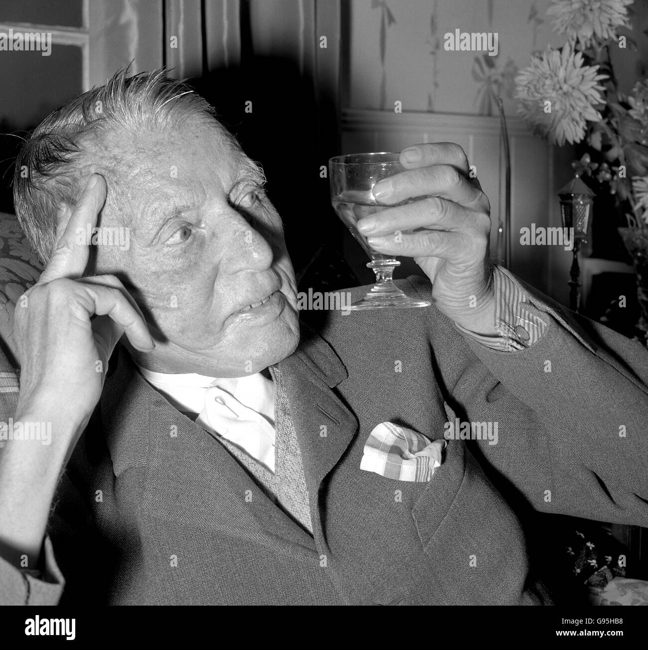 A. E. Matthews drinks a toast to the future in his Bushey Heath home