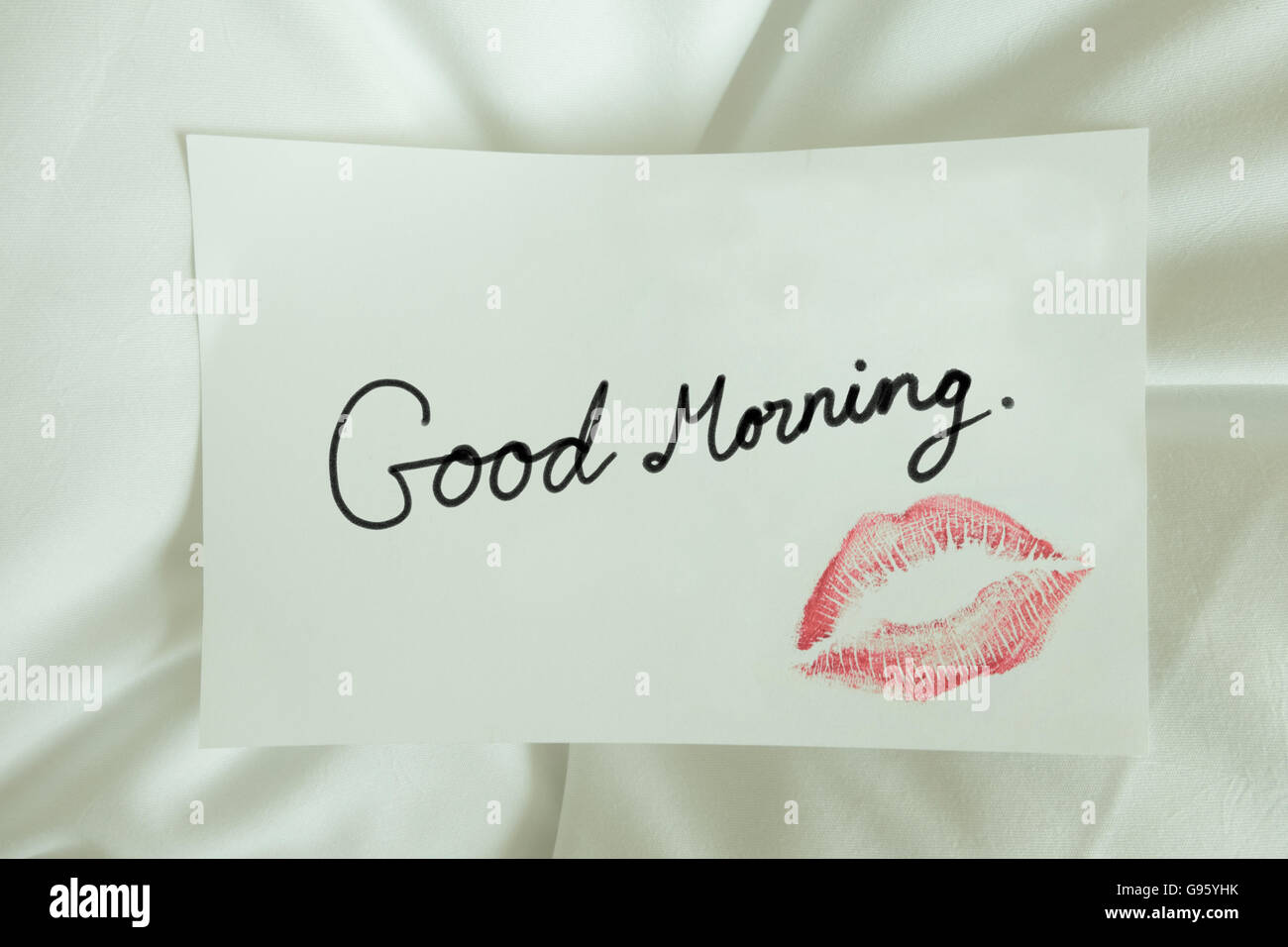 Sexy girl Red lips kiss and 'Good Morning' write on blank white note paper on white bed in the morning light.  romantic message Stock Photo