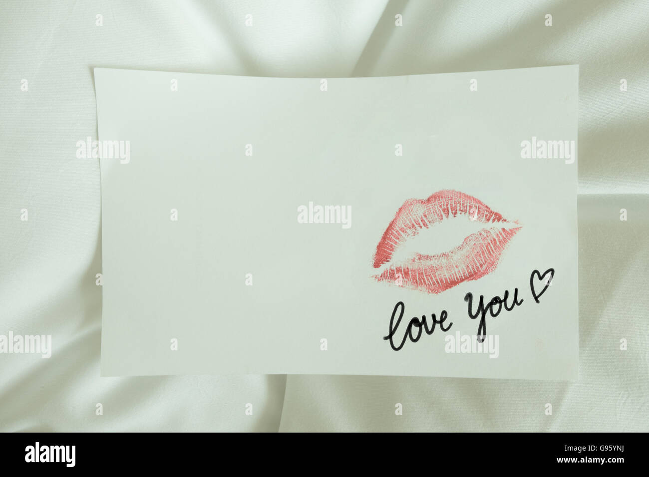 Sexy girl Red lips kiss love you write on blank white note paper on white bed in the morning light. romantic couple message Stock Photo