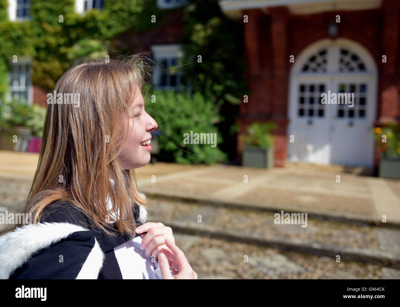 Smiling student celebrates graduation at Cambridge University wearing