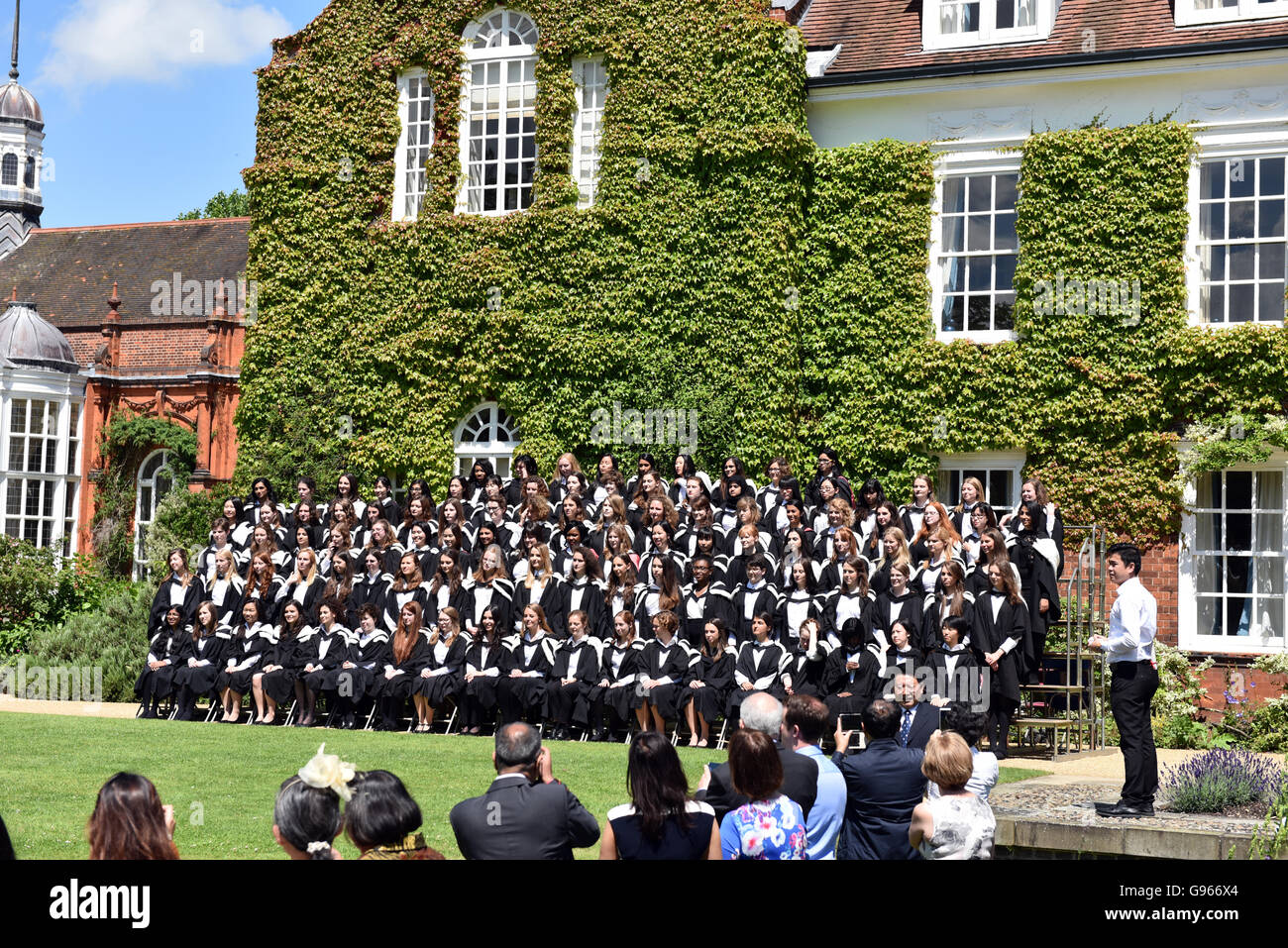 Students are assembled at Newnham college Cambridge for their graduation photo wearing fur lined hoods and gowns Stock Photo