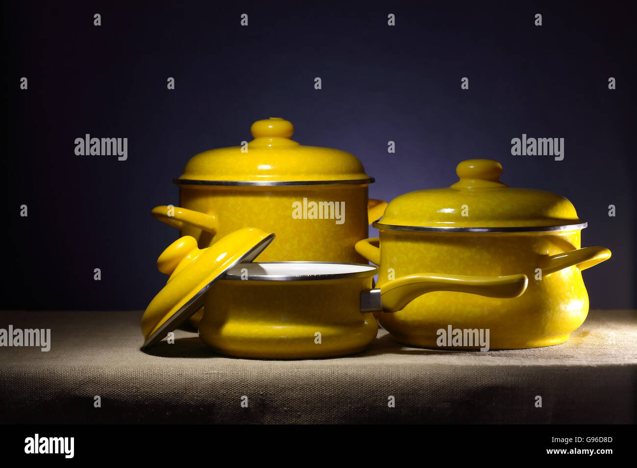 Still life with three yellow saucepans on dark background Stock Photo