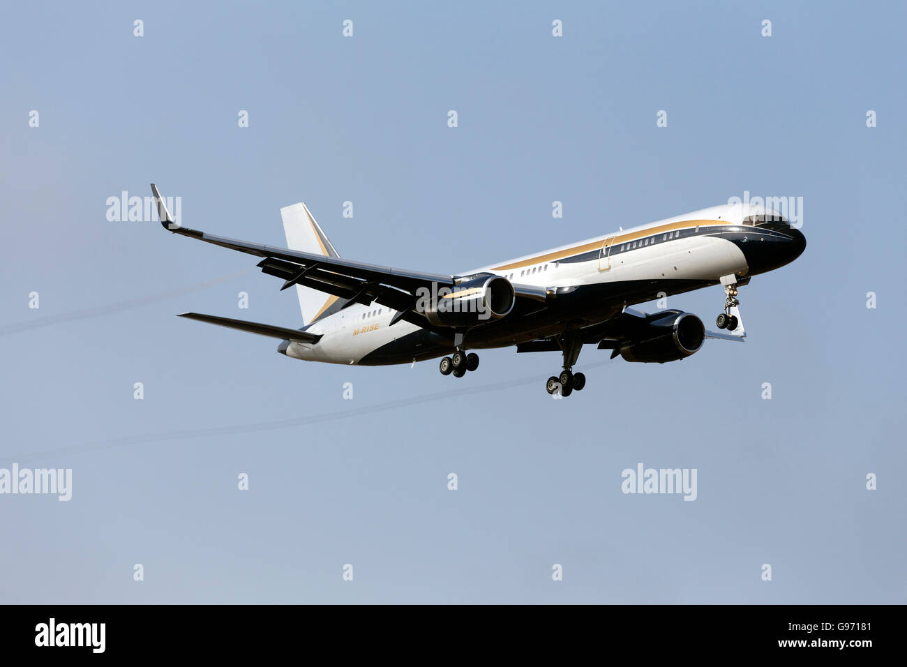A private Boeing 757-200 (C-32) [M-RISE] on finals for runway 31 trailing vapor trails on a humid morning. Stock Photo