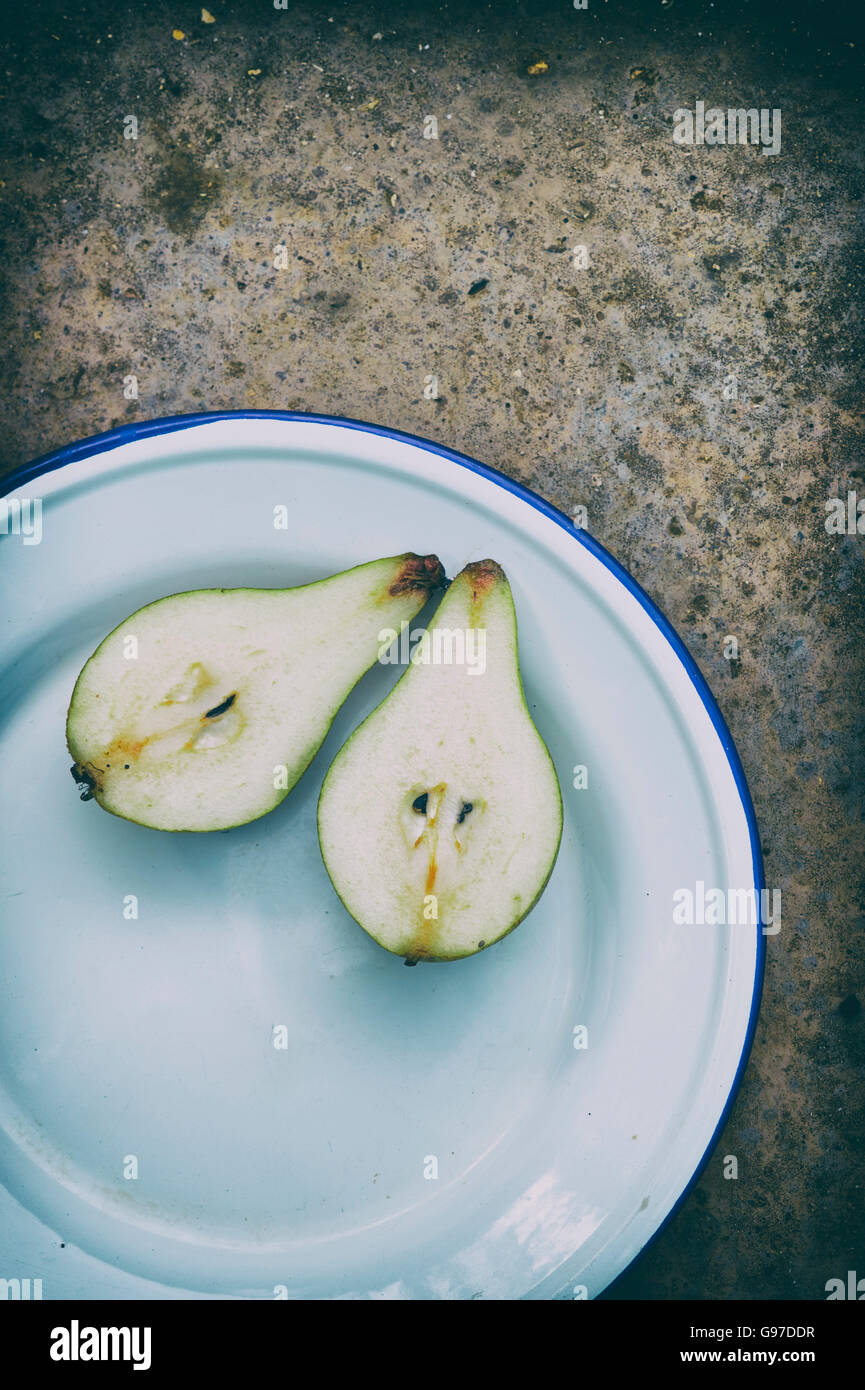 Cut pear on an enamel plate. Vintage filter applied Stock Photo