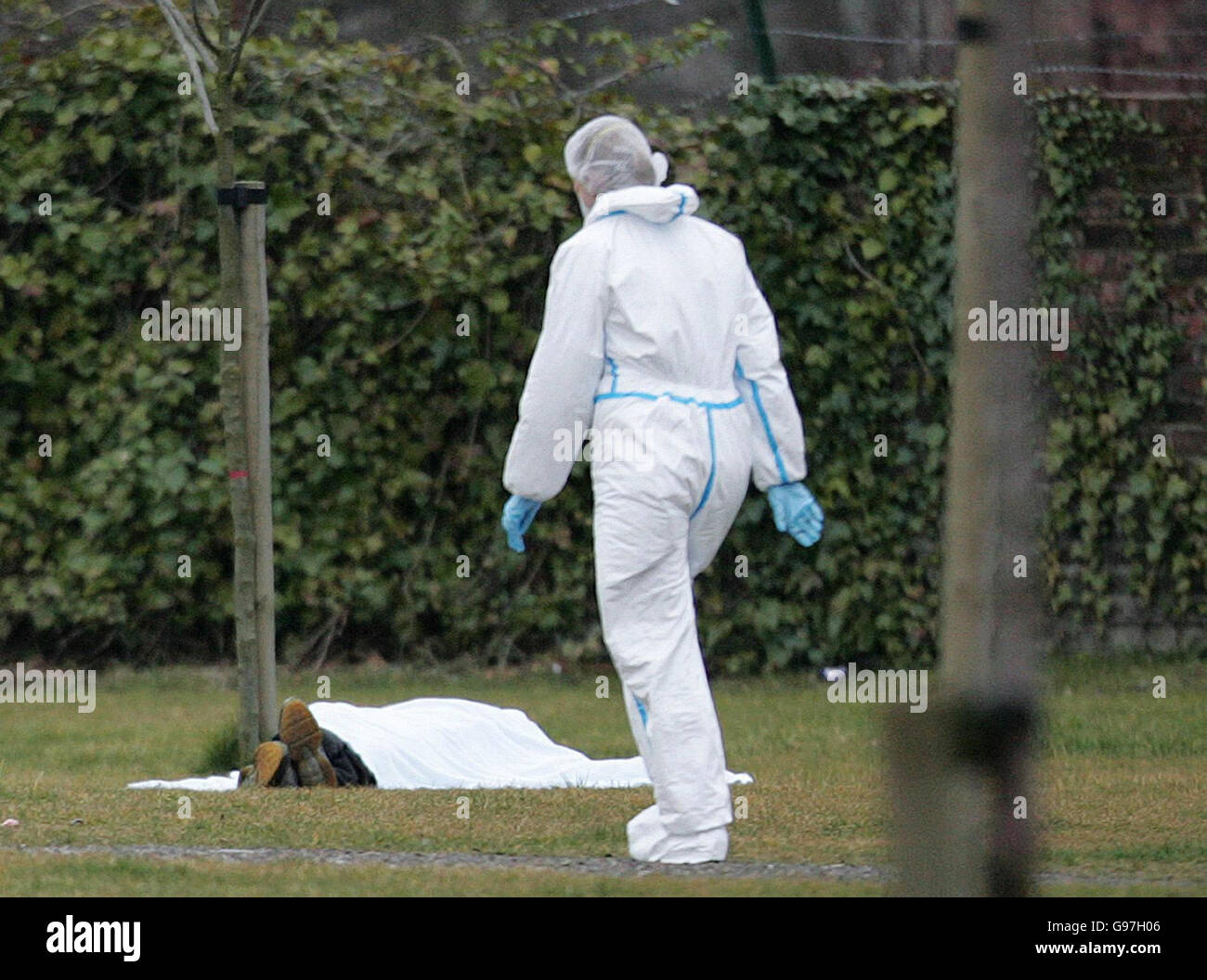 NOTE GRAPHIC CONTENT. A police forensic officer walks past a covered body after a shooting near the Brass Handles pub in Salford, Manchester, Sunday March 12, 2006. Two people were killed and two others were injured after the shooting, police said today. Officers were called to the pub at around 2.30pm today after reports of gun shots. The two injured people were taken to hospital but the extent of their injuries is unknown. See PA Story POLICE Shooting. PRESS ASSOCIATION Photo. Photo credit should read: Martin Rickett/PA. Stock Photo