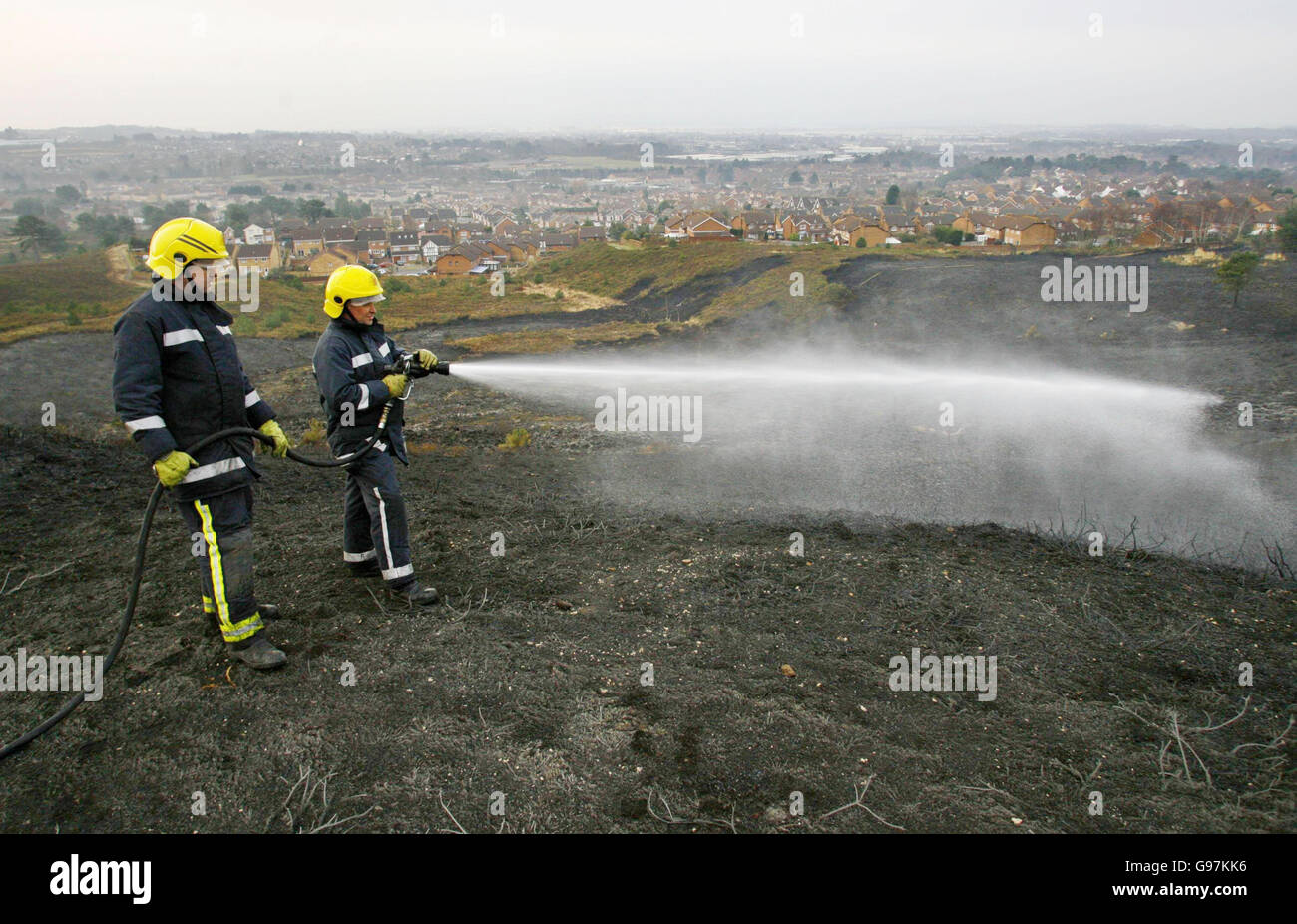 Dorset firefighter Matt Norman (with hose) and crew manager Nick Corben on Canford Heath in Poole Monday March 20, 2006, where they were damping down hotspots left after a wildfire destroyed a large area of the heath. Around 100 people evacuated from their homes have now been allowed to return. Twenty-five fire engines and 12 Land Rovers were involved in the battle last night to get the blaze under control. See PA story FIRE Heath. PRES ASSOCIATION Photo. Photo credit should read: Chris Ison / PA Stock Photo