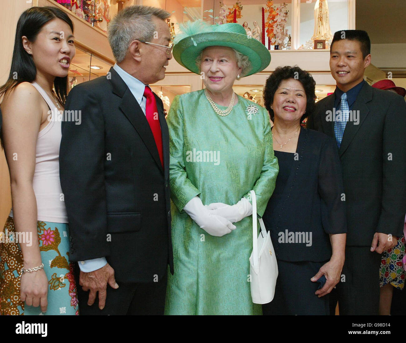 Britain's Queen Elizabeth II is greeted by Thomas Pung (2nd left) and his  family (L-R) daughter Genevieve, wife Limpoh Siock and son Ivan Michael,  during a revisit to the Pung family on