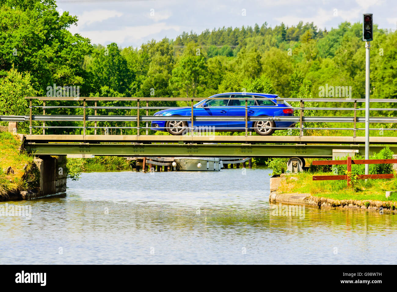 Bjornavad, Sweden – June 20, 2016: Blue car driving over retractable rolling bridge over Gota canal. Stock Photo