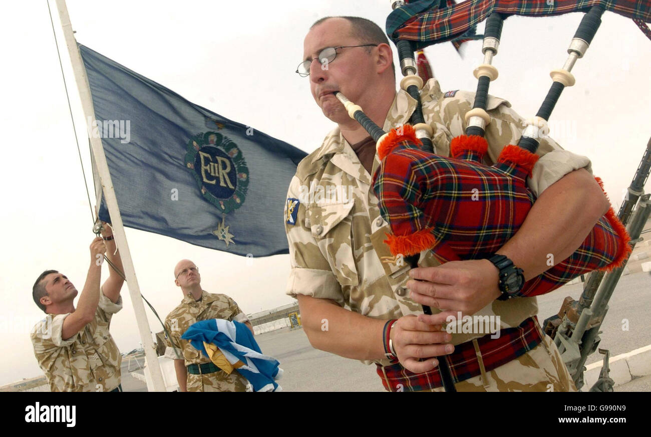 Corporal William Taylor of the former Royal Scots regiment plays the bagpipes as the old regiment's flag is lowered for the last time during a re-badgeing ceremony for the new Royal Regiment of Scotland (RRS) at the Shaibah logistic base in Basra, southern Iraq, Tuesday March 28, 2006. Ceremonies also took place today in Edinburgh, Cyprus and Belfast to mark the merger of six Scottish regiments to form the RRS. See PA story DEFENCE Regiments. PRESS ASSOCIATION photo. Photo credit should read: Danny Lawson/PA. Stock Photo