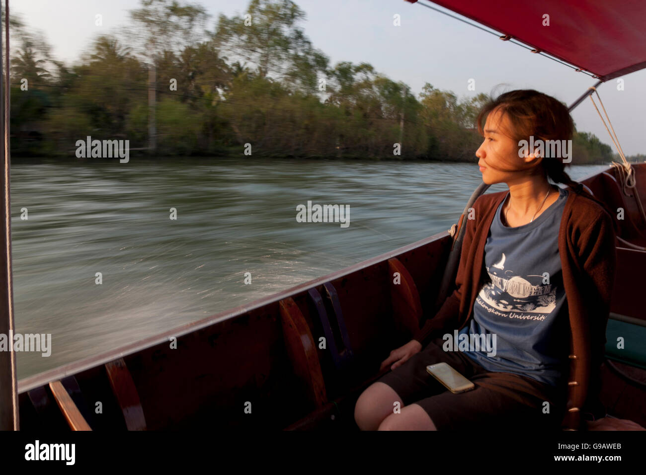 A Thai woman sitting in a longtail boat on the Maeklong River in Thailand. Stock Photo