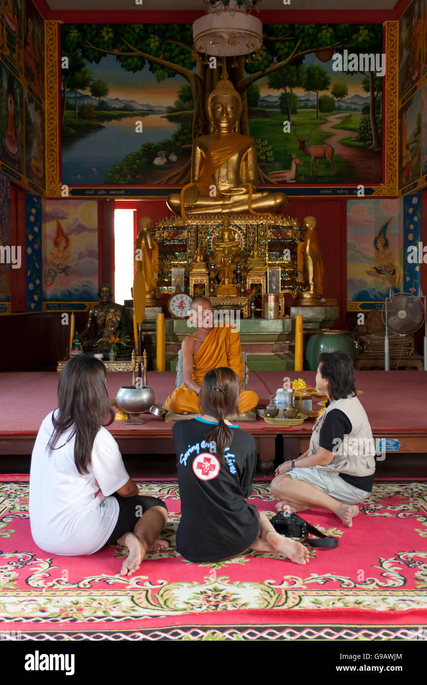 A group of Thais talking to a monk after conducting prayers in the main temple hall of Wat Phummarin in Maeklong in Thailand. Stock Photo