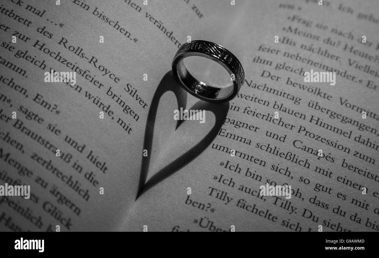 Ring casts a heart-shaped shadow in book. Stock Photo