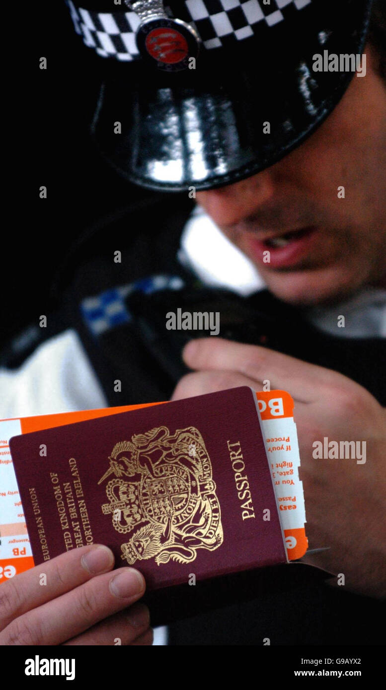 A British Police Officer checks a passport at Stansted airport Essex, ahead of the start England's World Cup campaign against Paraguay on Saturday in Frankfurt. Stock Photo
