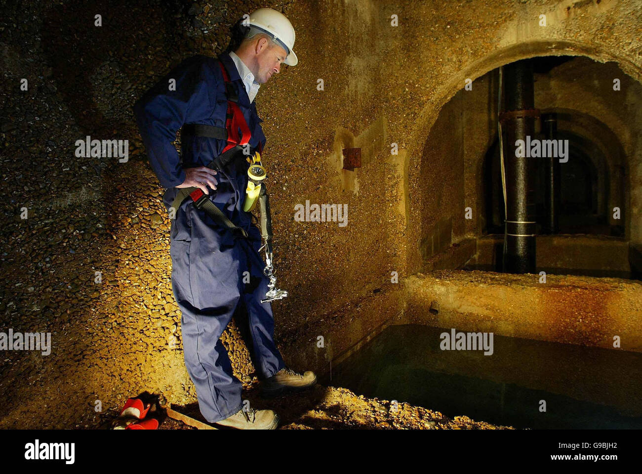 Regional production manager at South East Water, Kevin Clark, looks into the water at the bottom of a borehole near Eastbourne, Sussex, in a chamber which should be submerged at this time of year. Stock Photo