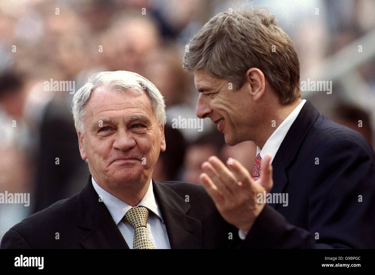 Newcastle United manager Bobby Robson (l) tries hard not to smile at a point made by Arsenal manager Arsene Wenger (r) Stock Photo