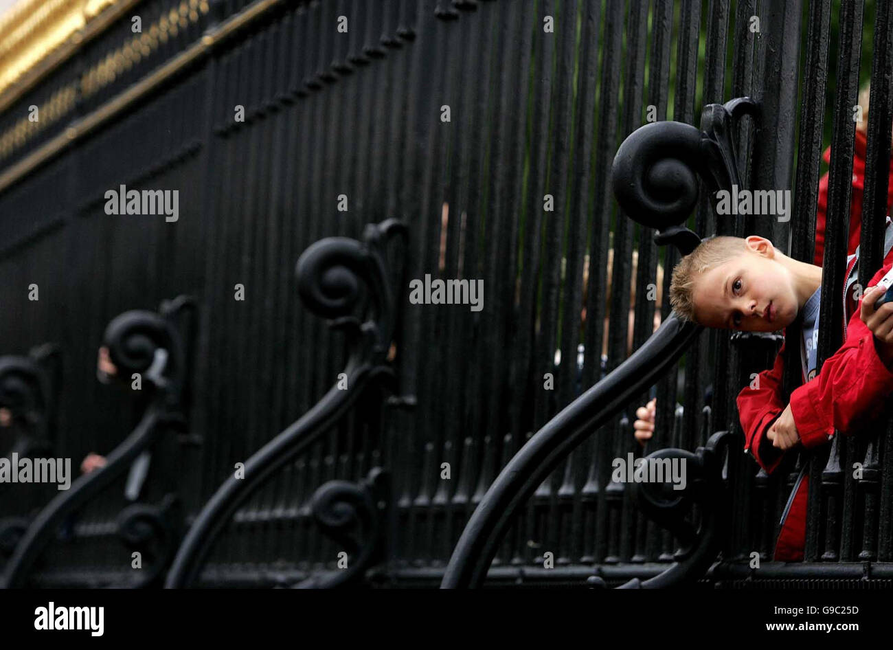 An un-identified child puts his head through the railings of Buckingham Palace, London, to get a better view of the Changing of the Guard. Stock Photo