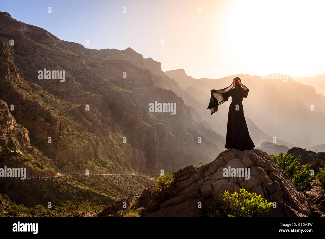 Lone woman in abaya in Al Hajar Mountains of Oman at sunset Stock Photo