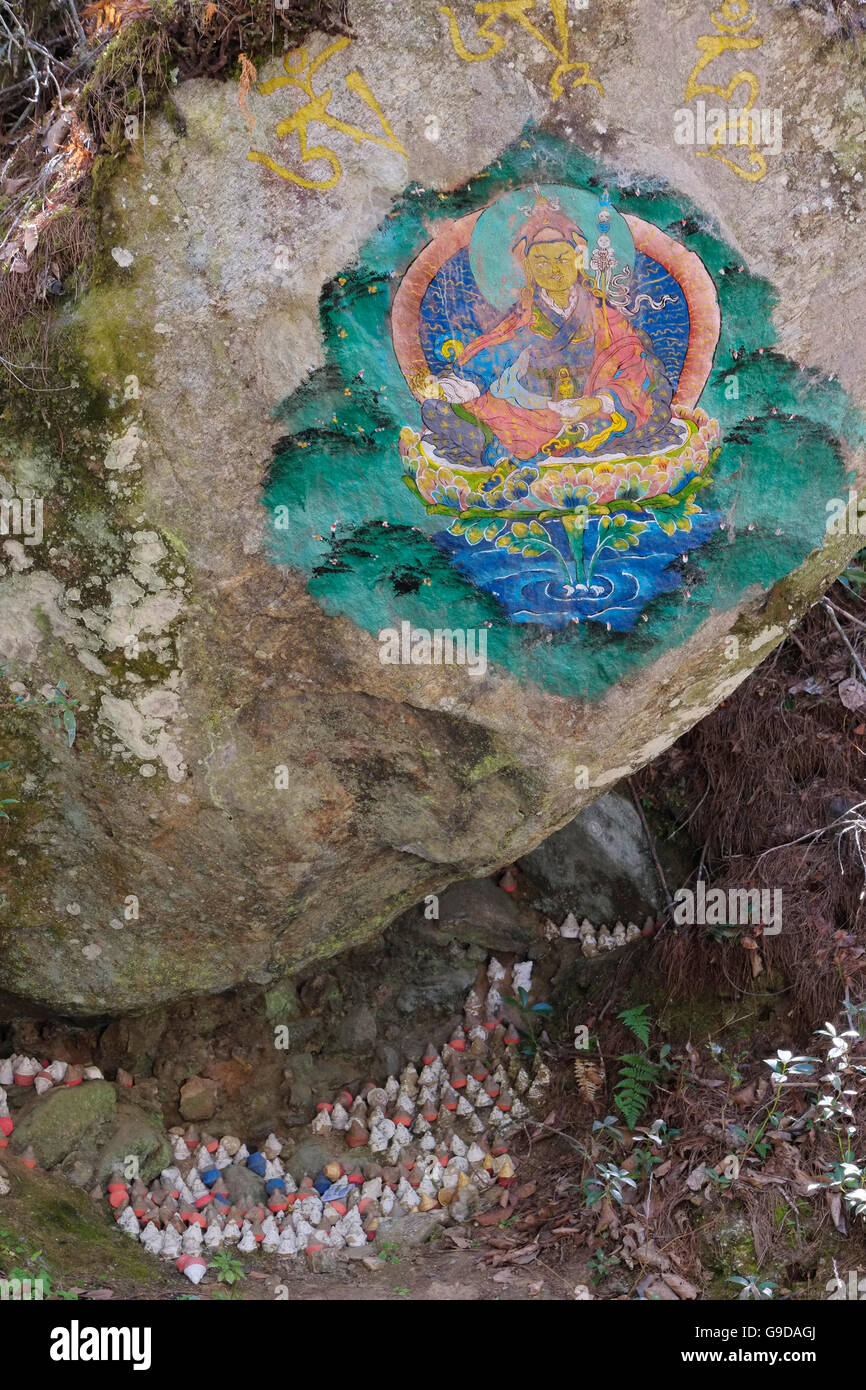 A Buddhist painting on a boulder with miniature clay stupas (tsa-tsa's) beneath. The Taktsang trail, Paro, Bhutan. Stock Photo
