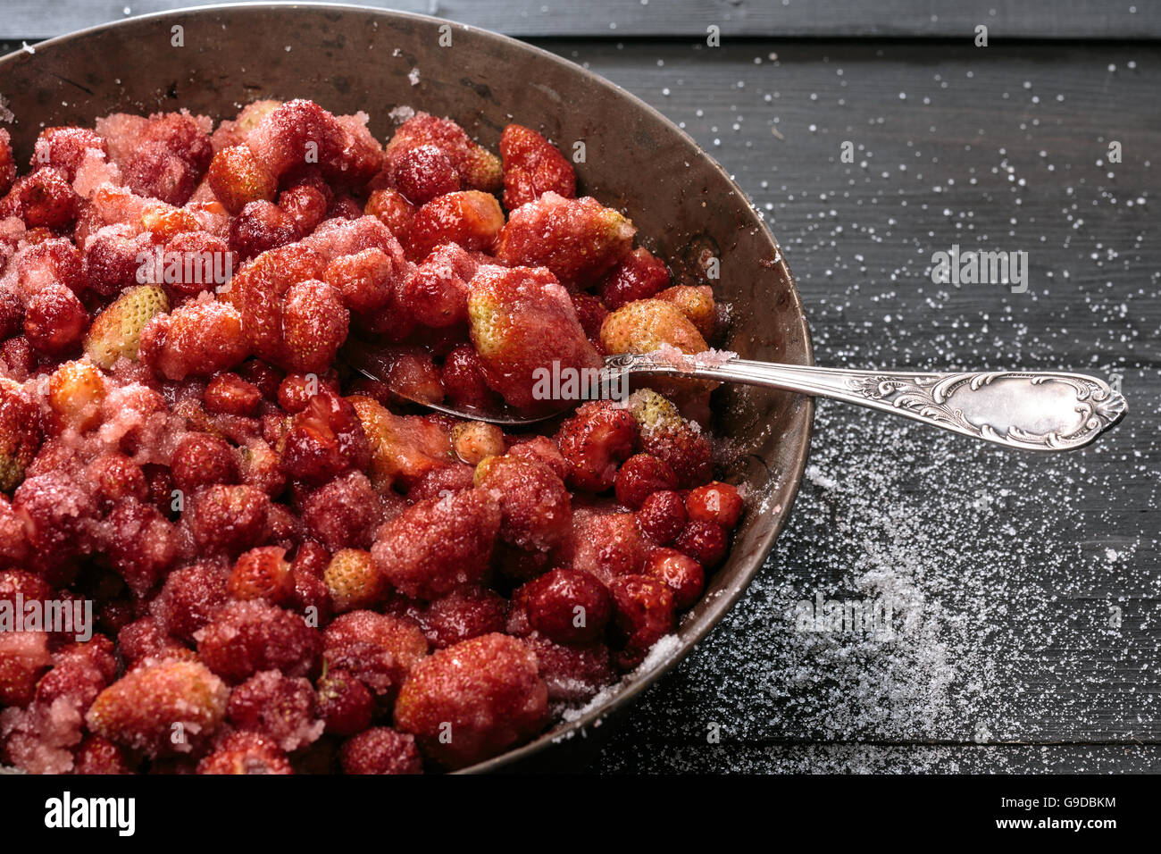 Strawberry Jam preparation. Berries mixed with sugar releasing its own juice. Selective focus on spoon Stock Photo