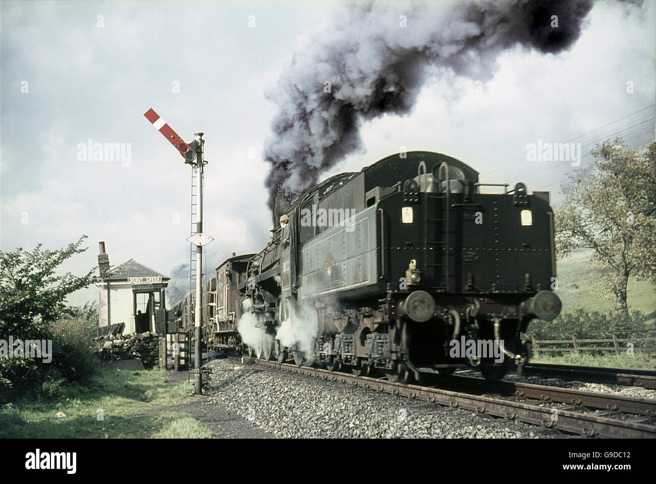 A BR standard 4 4–6–0 passes Scout Green Signal box whilst banking a heavy freight up Shap Bank. Stock Photo
