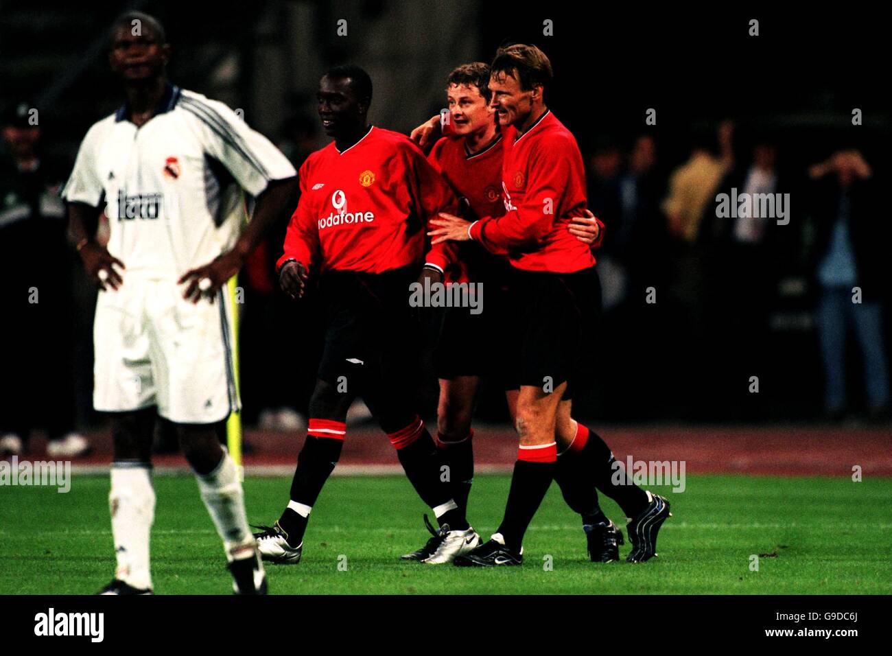 Manchester United's Teddy Sheringham (r) and Dwight Yorke (l) congratulate Ole Gunnar Solskjaer (c) after he scored the winning goal, much to the disgust of Real Madrid's Samuel Eto'o (far left) Stock Photo