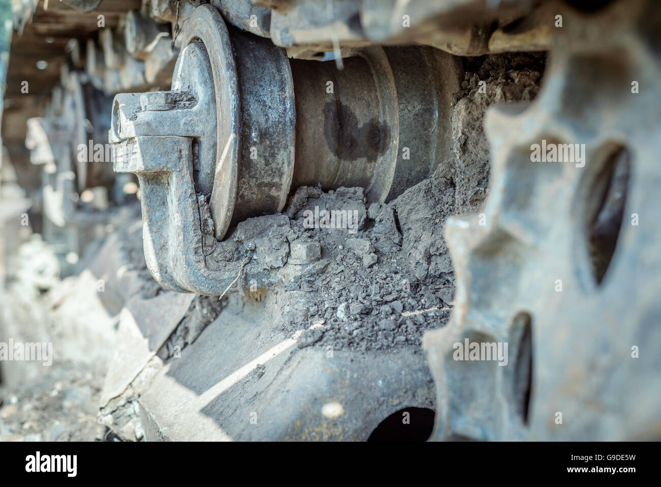 Aged abandoned industrial machine with corroded dirt stained caterpillar tracks and cogs. Stock Photo