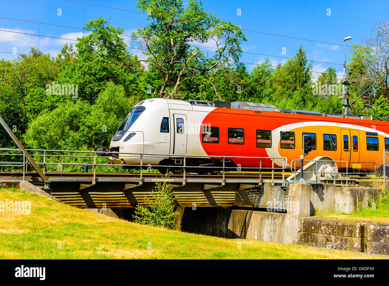 Norsholm, Sweden - June 20, 2016: Colorful train passing over a movable bridge crossing the Gota canal. Stock Photo